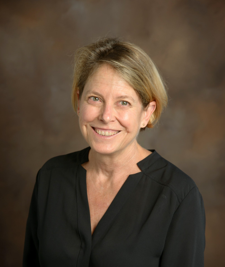 Woman with short hair smiles into the camera.