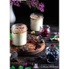 Mason jars with porridge on a black background with flowers, blueberries, mint, and shaved dark chocolate