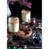 Mason jars with porridge on a black background with flowers, blueberries, mint, and shaved dark chocolate